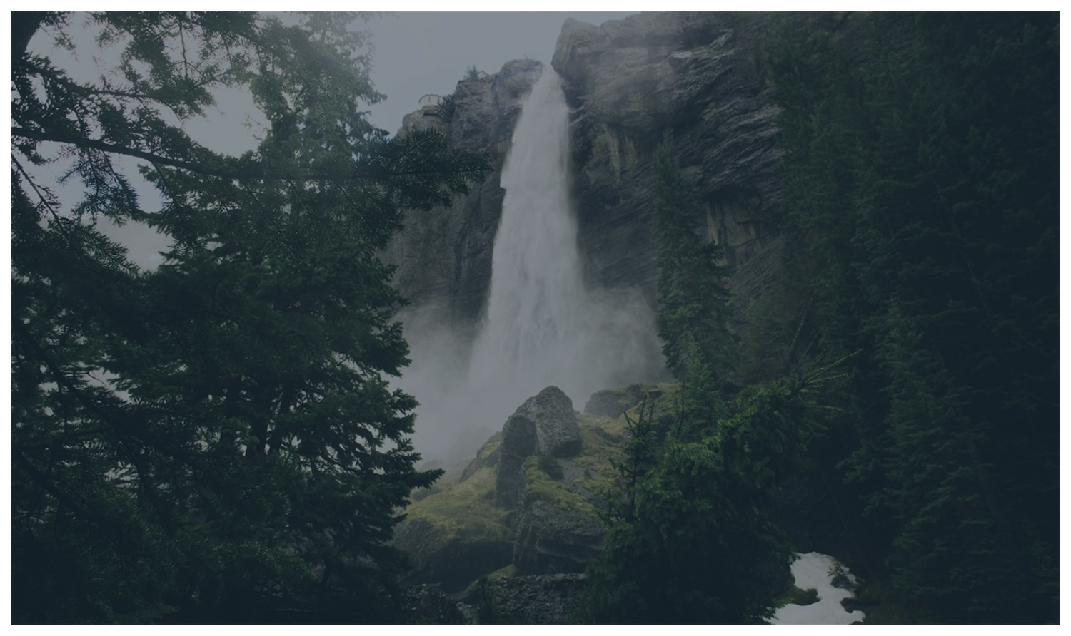 A towering waterfall plunging down a misty cliff face into deep evergreen forest